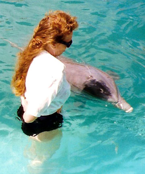 Karen Duquette touching a dolphin